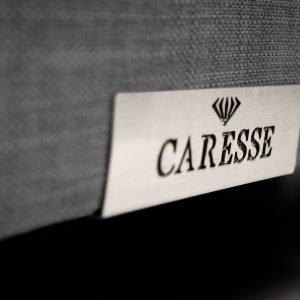 detail van metalen caresse logo op de boxspring