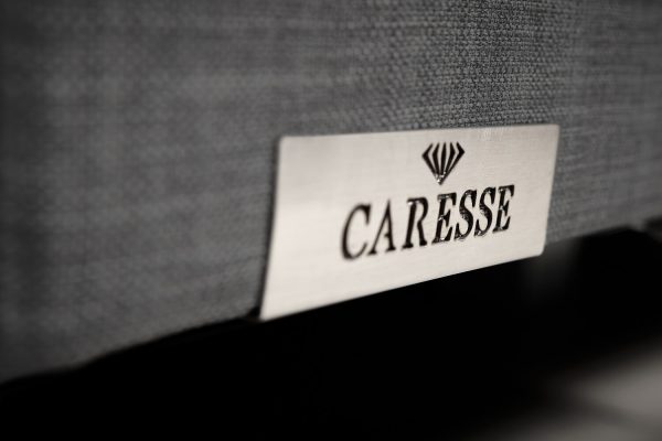 detail van metalen caresse logo op de boxspring