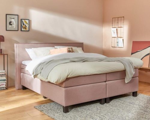 roze opgedekt boxspring bed in een lichte kamer