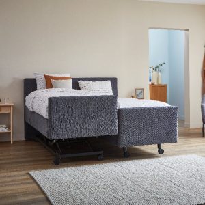 Grijs boxspring bed op wielen wat aan een kant hoog laag kan en aan een kant verstelbaar is